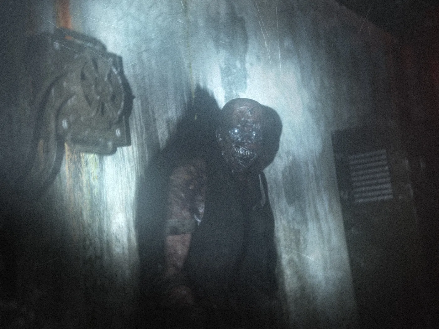 A decayed humanoid figure stepping out of a dark, stained concrete wall.